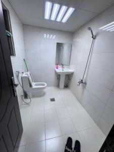 a white bathroom with a toilet and a sink at Royal International in Abu Dhabi