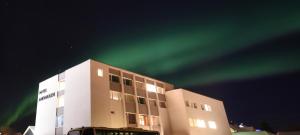 an office building with the green northern lights in the sky at Thon Partner Hotel Andrikken in Andenes