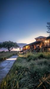a building with a path next to a river at Elewana Sand River Mara in Talek