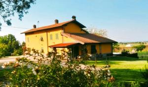 a small yellow house in a field of grass at Cascina Rocchino bed and breakfast in Predosa