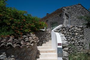 a stone wall with stairs next to a building at Maison Henriette - Authentique maison ardéchoise in Labeaume