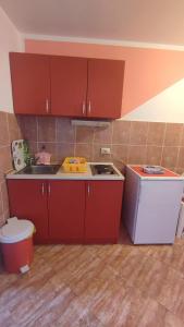 a kitchen with red cabinets and a sink and a refrigerator at Apartmani Šušanj in Bar