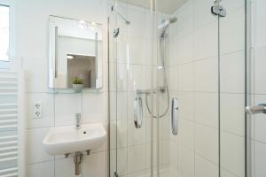 a white bathroom with a sink and a shower at Sonneneck in Westerland +23 photos