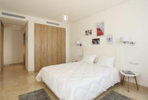 a white bedroom with a large white bed and a table at La Brise De Gammarth in Gammarth +5 photos