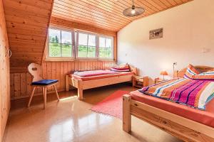 a bedroom with two beds and a chair in a cabin at Wiesenglück in Abtsgmünd +2 photos