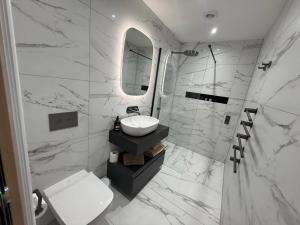 a white bathroom with a sink and a mirror at Auberge Hotel by Sasco in Lytham St Annes