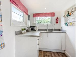 a kitchen with white cabinets and a sink at Lovers Carriage - Uk46404 in Cowbridge