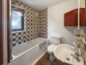 a bathroom with a tub and a toilet and a sink at Bramble Grange in Derby