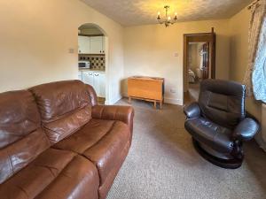 a living room with a leather couch and a chair at Bramble Grange in Derby