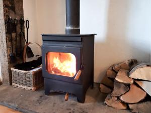 a stove with a fire in a room with logs at Chapel Cottage in Askham +5 photos