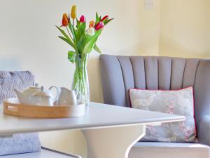 a vase of flowers sitting on a table next to a chair at Priest Hill-Rxx7 in Stanton in Peak