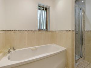a bathroom with a white tub and a shower at Derwen Haidd in Llanafan
