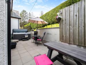 a patio with a wooden bench and an umbrella at Derwen Haidd in Llanafan +17 photos