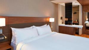 a bedroom with a large white bed and a bathroom at AC Hotel by Marriott Minneapolis Downtown in Minneapolis