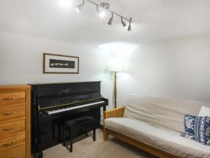a living room with a piano next to a couch at Sheldon Cottage in Bishops Castle