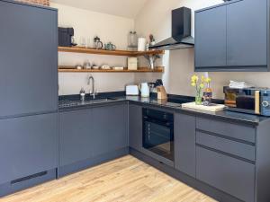 a kitchen with blue cabinets and a sink at Maple Barn in Eye