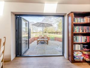 an open door to a patio with an umbrella at Maple Barn in Eye +7 photos