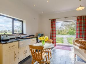 a kitchen with a table with a vase of flowers on it at Pettingalls Farm Cottage in Great Ellingham