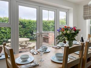 a dining room with a wooden table with flowers on it at Old Master's Cottage in Leven +17 photos