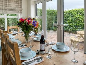 a dining room table with a bottle of wine and flowers at Old Master's Cottage in Leven