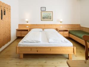 a bedroom with two beds and a green bench at Hotel Hello in Monguelfo