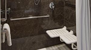 a bathroom with a black tiled shower with a toilet at AC Hotel by Marriott Minneapolis Downtown in Minneapolis +53 photos