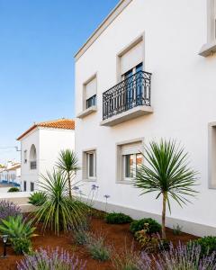 a white building with a balcony and palm trees at S'apartments in Leiria
