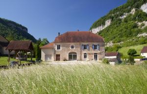 a large stone house in front of a mountain at Du Baume Au Cœur in Baume-les-Messieurs