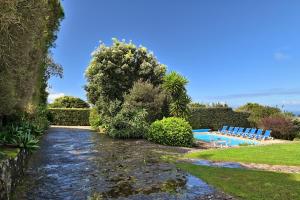 a garden with a swimming pool and blue chairs at Casa do Moinho in Ulgueira