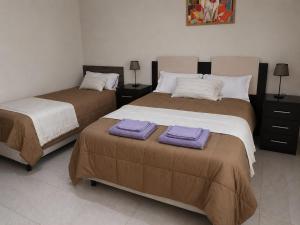 two beds in a room with purple towels on them at Talahuasto in Los Baldecitos