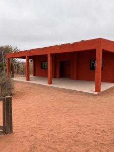 a red building in the middle of a dirt field at Talahuasto in Los Baldecitos +2 photos