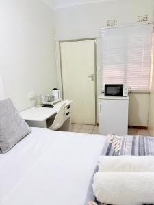 a white bedroom with a bed and a sink at Paradise Corner in Francistown