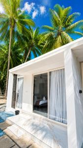 a white house with palm trees in the background at Beachside Agatti Resort in Agatti