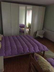 a bed with a purple cover on it in a room at Spacious and Charming House in Vozuća with Large Garden in Vozuća