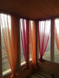 a room with three windows with red curtains at Spacious and Charming House in Vozuća with Large Garden in Vozuća