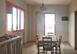 a dining room with a table and a kitchen with windows at Charming House in Gallipoli + Terrace in Gallipoli