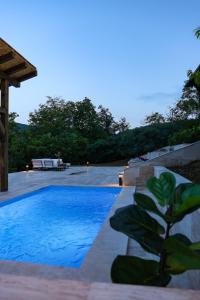 a swimming pool in front of a house with a bench at Dedovina Pakovraće in Čačak