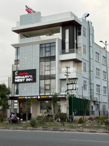 a large white building with a sign on it at Senary's Nest INN in Kyātsandra