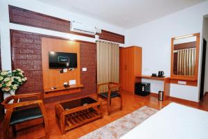a room with a tv and a table and chairs at Apoorva River Resort in Māvingundi