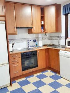a kitchen with wooden cabinets and a checkered floor at Comfortable Apartment in Astorga + Terrace in Astorga