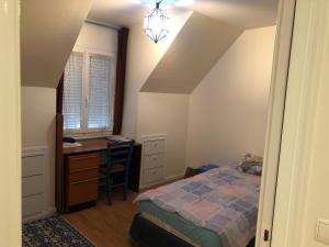 a bedroom with a bed and a desk and a window at Appartement cosy à Sannois de 110 m² avec jardin clôturé in Sannois