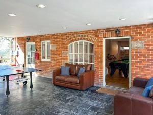 a living room with a ping pong table and a brick wall at Ible Cottage - Qve in Hognaston +1 photo