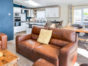 a living room and kitchen with a leather couch at Serenity At Lakeside - Uk51947 in Patrington