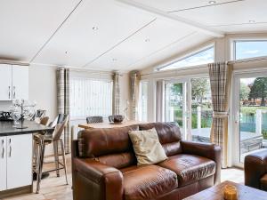 a living room with a leather couch and a kitchen at Serenity At Lakeside - Uk51947 in Patrington