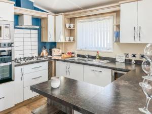a kitchen with white cabinets and a black counter top at Serenity At Lakeside - Uk51947 in Patrington +11 photos