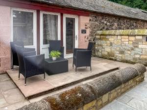 a patio with chairs and a table in front of a building at Stewards Bothy - Uk48303 in Berwick-Upon-Tweed