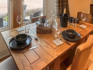 a wooden table with black plates and wine glasses at Stewards Bothy - Uk48303 in Berwick-Upon-Tweed