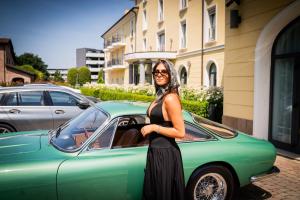 a woman standing next to a green car at Maranello Palace in Maranello