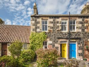 an old stone house with a yellow and blue door at Struan in Kilconquhar