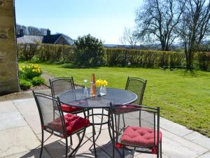 a table with chairs and a bottle of wine on it at Keepers Cottage Burradon in Sharperton